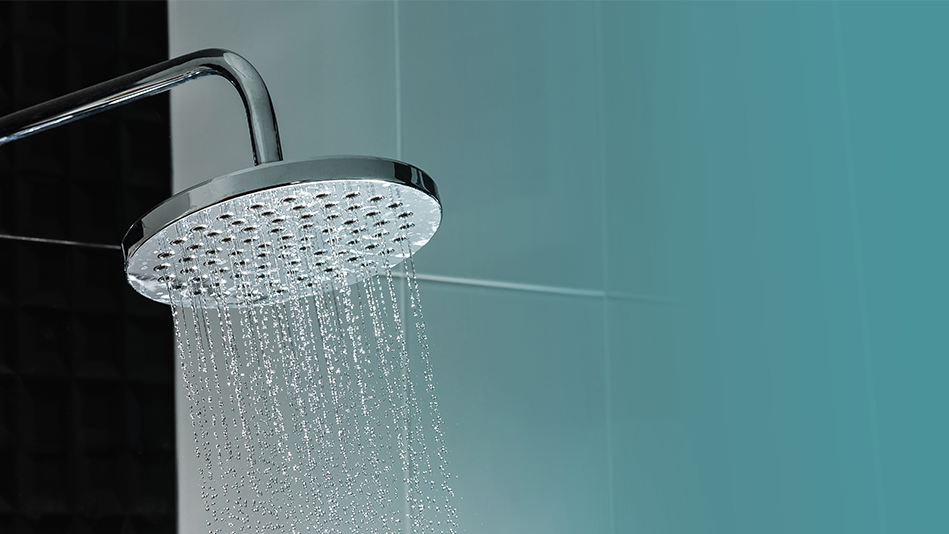 Stainless showerhead sprays water in front of a black and blue wall