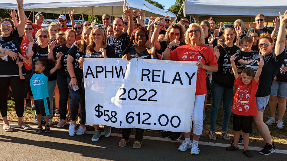 APHW employees pose behind a sign of the funds raised for Relay for Life in 2022