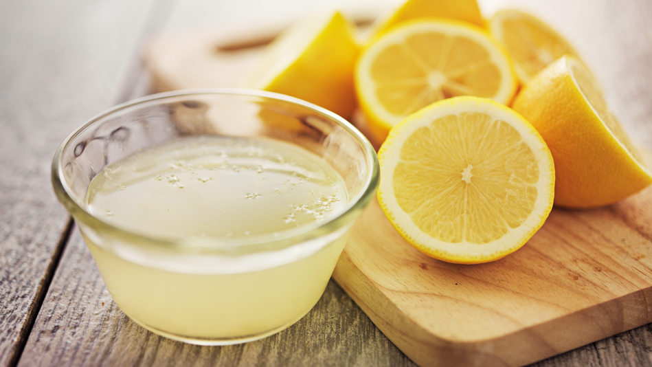 A bowl of lemon juice and some halved lemons