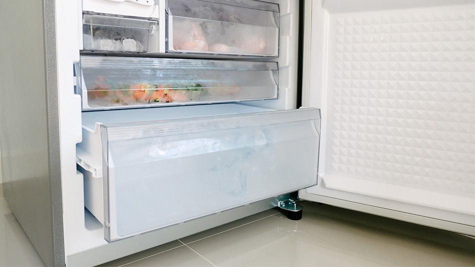 A tall freezer is open to reveal the frosted shelves inside