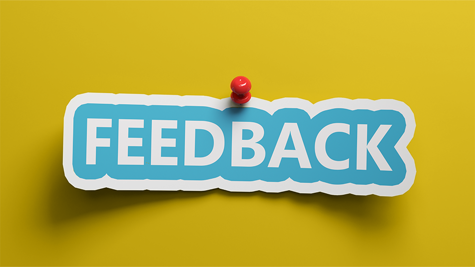 "Feedback" sticker tacked to a yellow wall