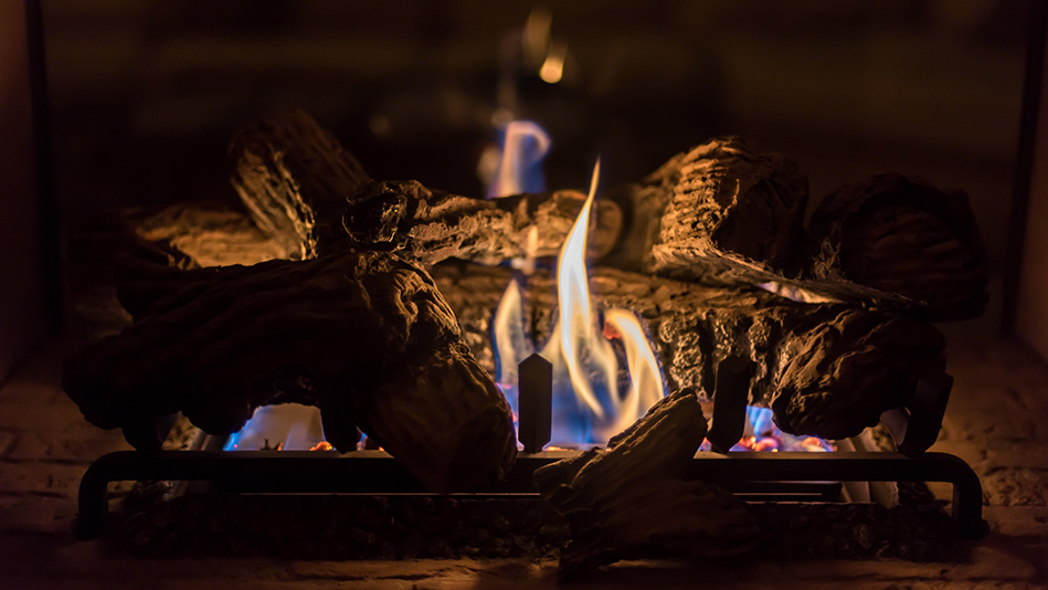 Flames flicker around the fake wood prop in a gas fireplace