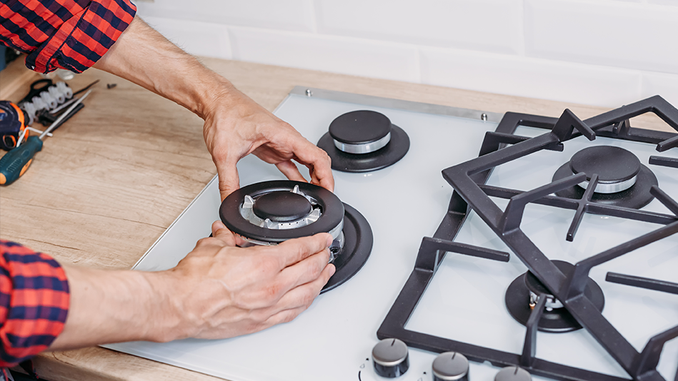 A licensed contractor's hands disassemble pieces of a gas stove