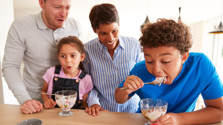 A Black woman and white man eat ice cream with their son and daughter; the boy consumes his excitedly, freaking everyone else out