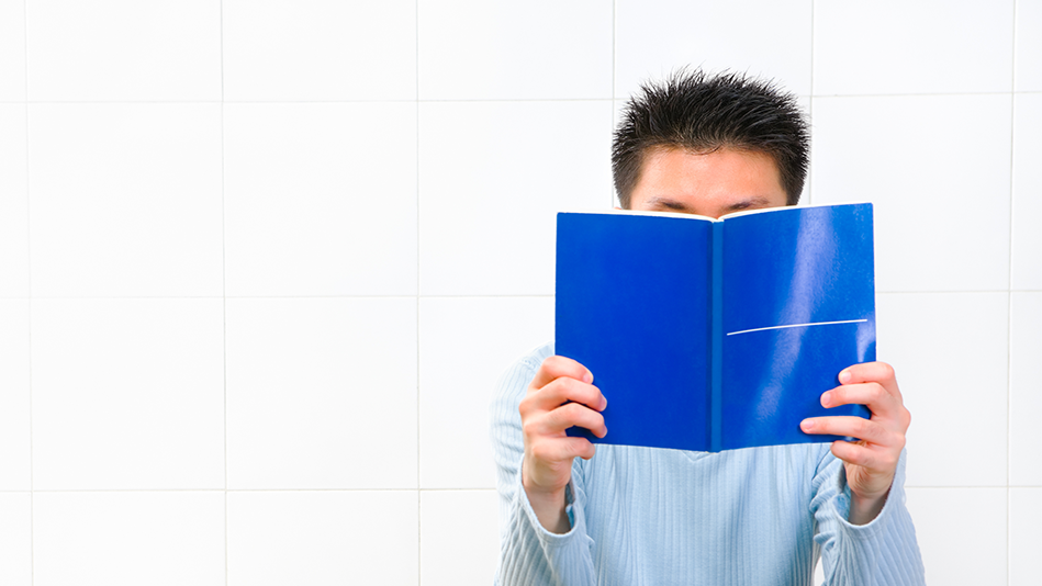 Man reads from a blue manual