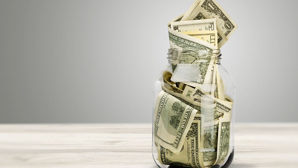 Assorted dollar bills are stuffed into a glass jar