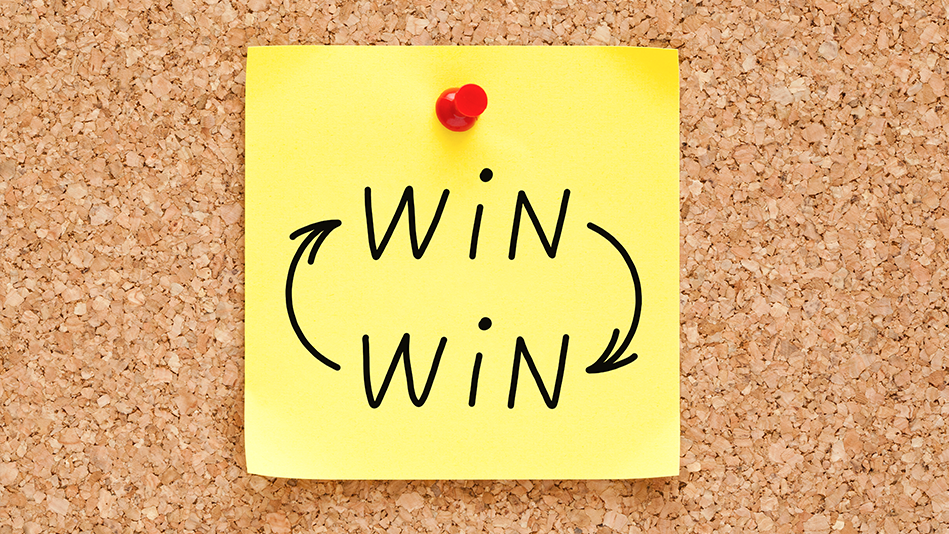A yellow sticky note says "WIN" twice, one stacked over the other, with one arrow pointing from each to the other; a red pushpin affixes it to the brown corkboard behind it  