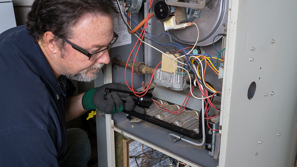 Middle-aged white male contractor works to light a pilot light on an appliance