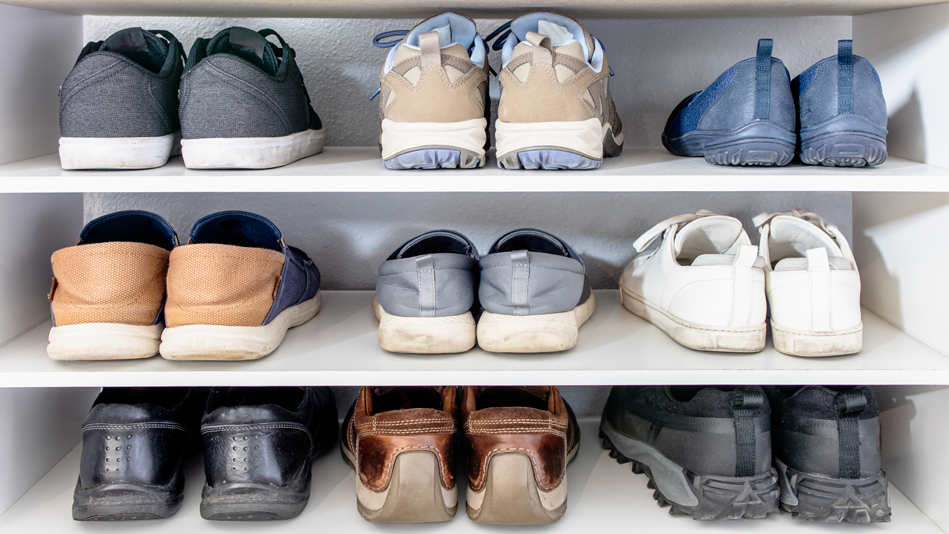 Three rows of neutral-colored shoes sit on three white wooden shelves, with three pairs of shoes on each shelf