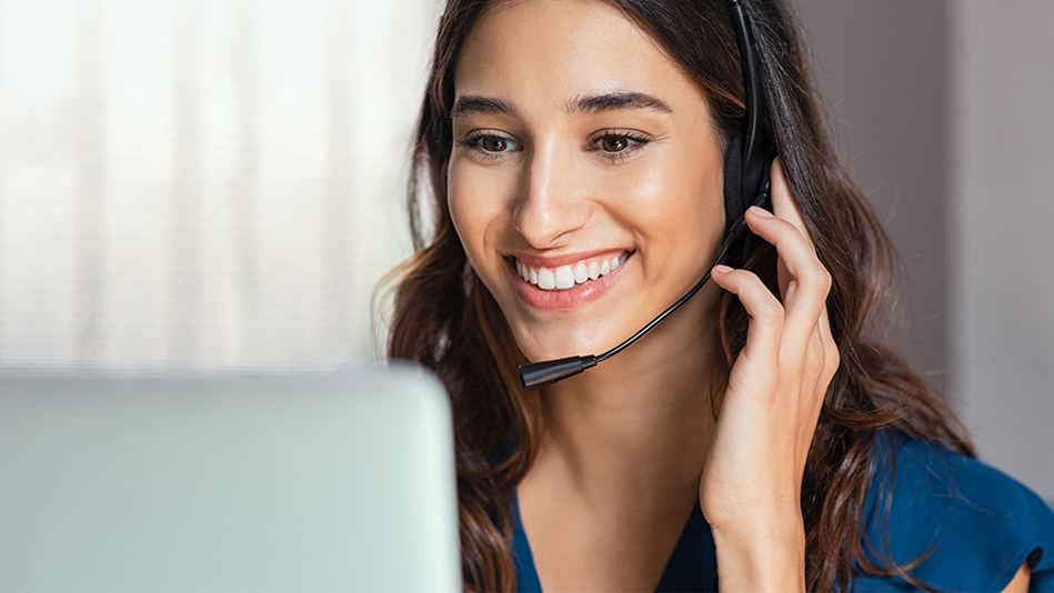 Caucasian woman adjusts her headset while smiling at a customer's comment