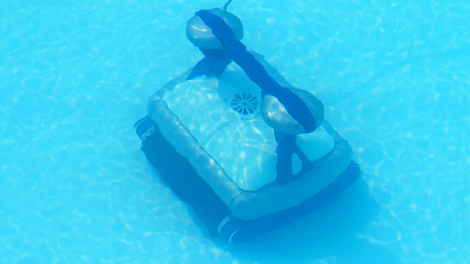 A robotic pool cleaner scrubs the bottom of a pool