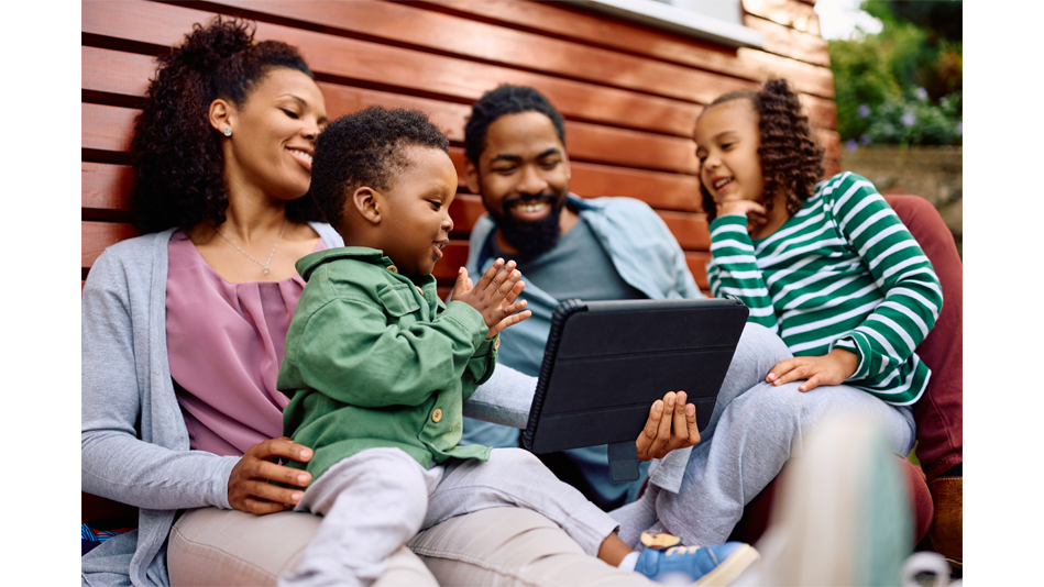 A black family of four share a tablet while outside