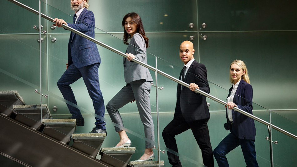 Multicultural business people walk up a staircase