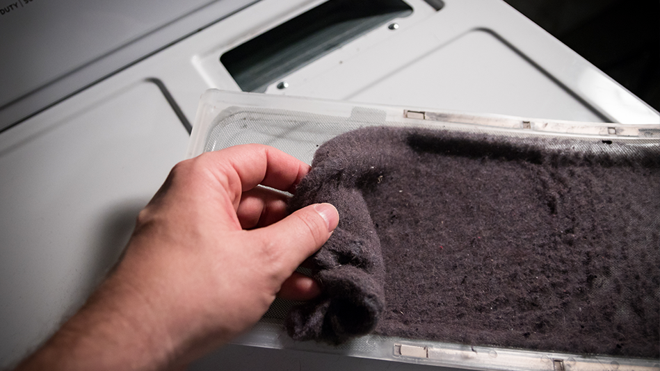 Someone pulls lint out of a dryer lint trap