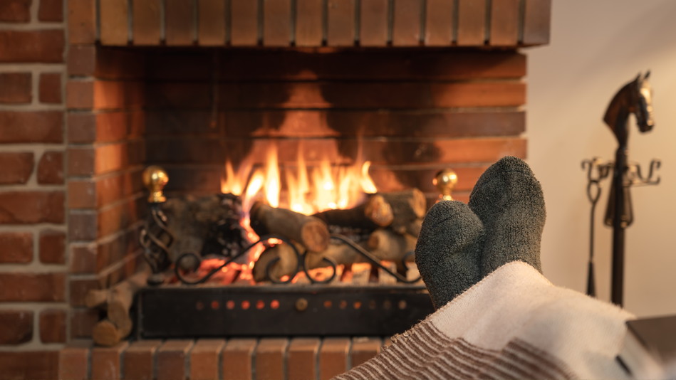 Someone lounges with their feet close to a warm gas fireplace