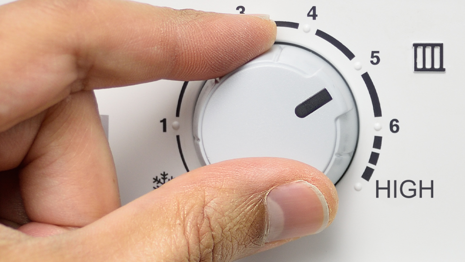 A hand turns knob to increase the temperature on an instant hot water dispenser