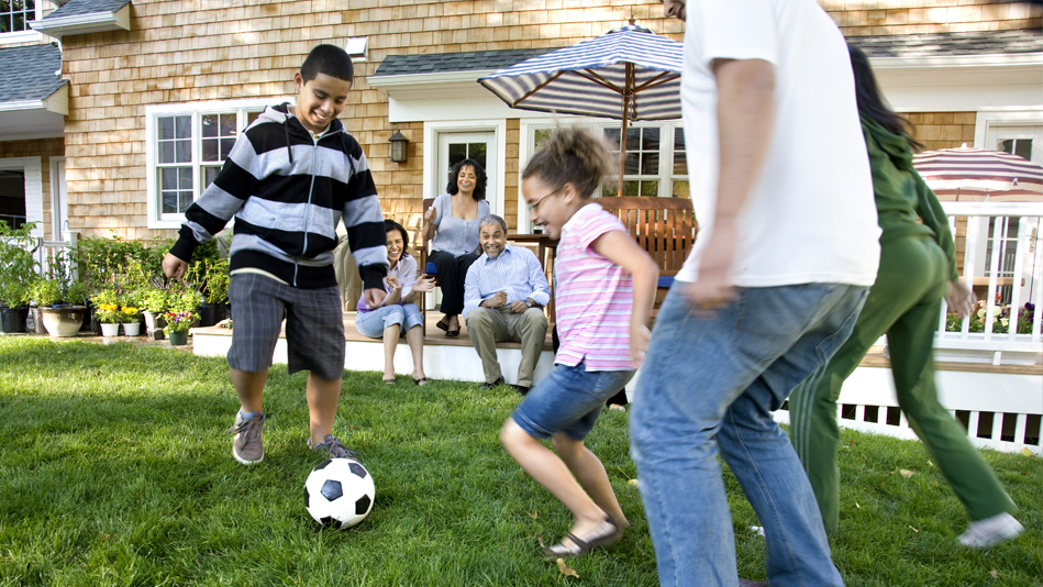 A multi-ethnic family plays soccer on the lawn