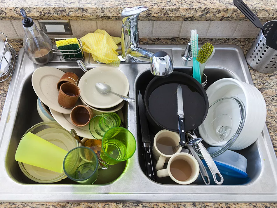 a metal kitchen sink full of dirty dishes