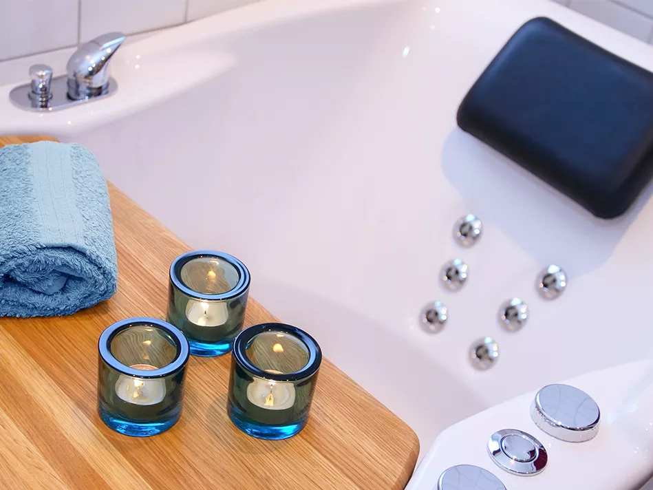 An empty jetted tub with a blue towel and 3 blue candlelights