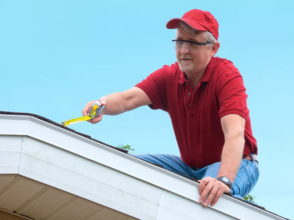 White older gentleman on a roof measures the angle of the roofline