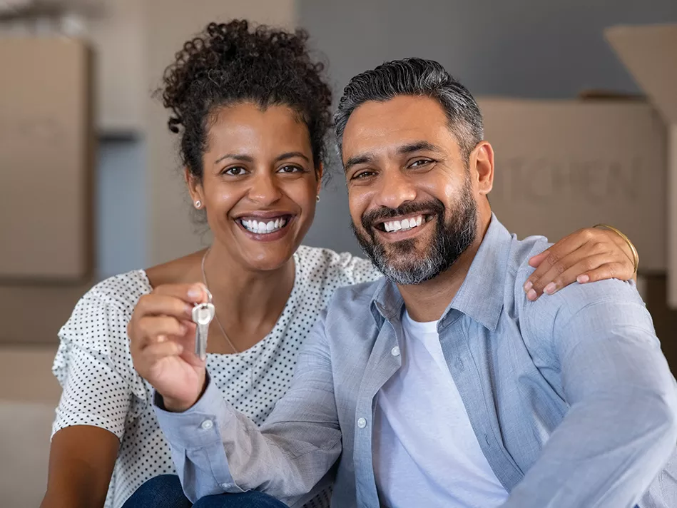 Blended man and woman smile while man holds keys