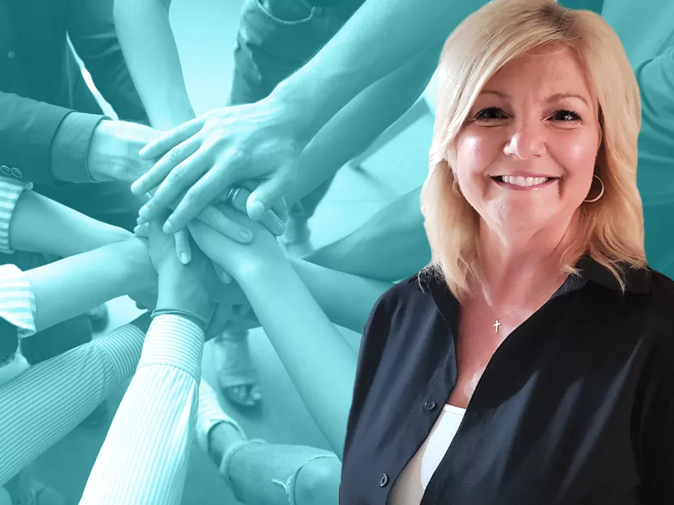 White female smiles in front of a group of hands coming in together as a team
