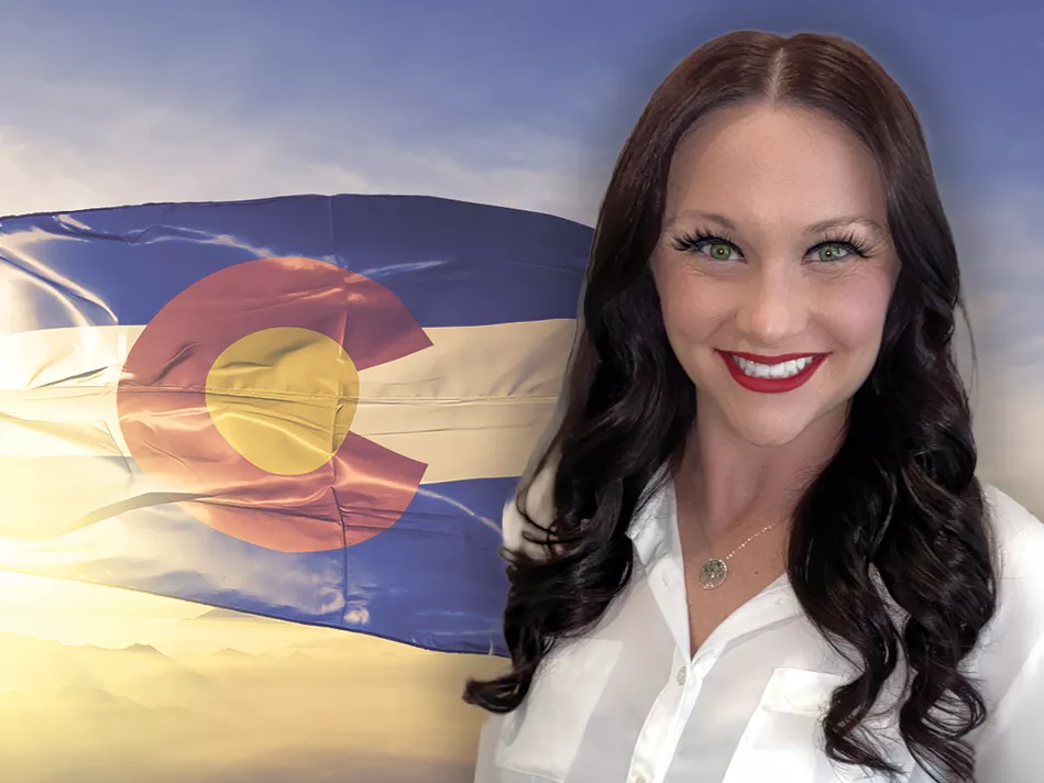 White woman with long dark hair smiles in front of the flag of Colorado