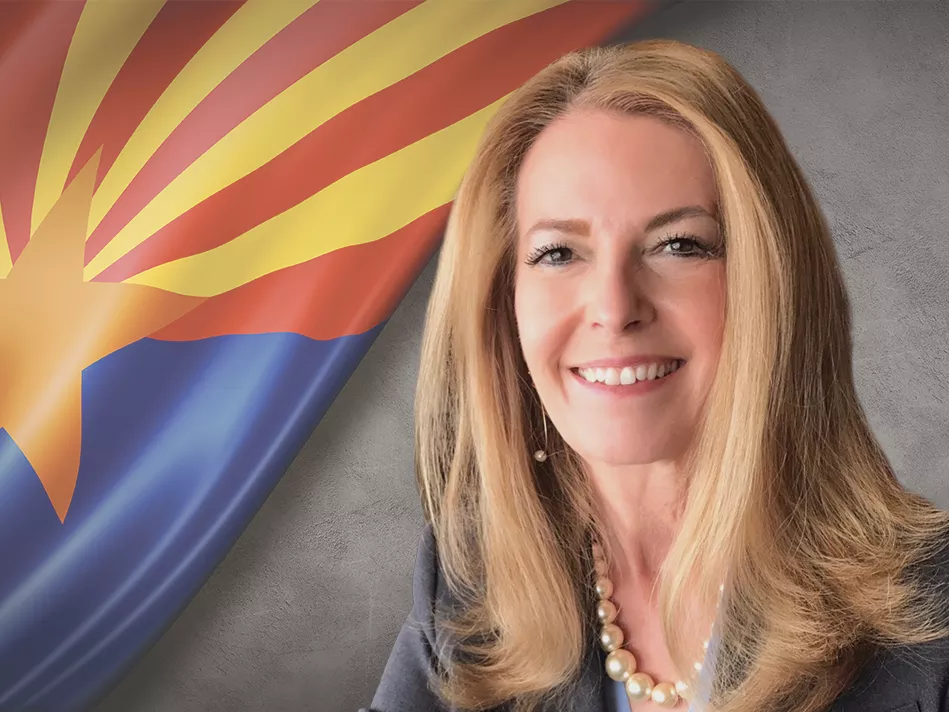 White businesswoman smiles in front of the Arizona state flag