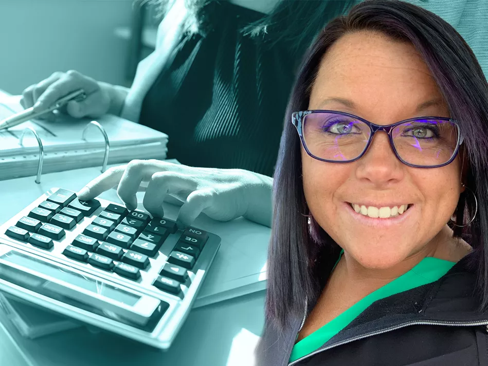 White woman with long dark hair and glasses smiles in front of an accounting background