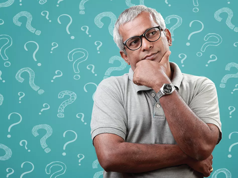 Silver-haired hispanic male stands in a thoughtful pose with question marks behind him