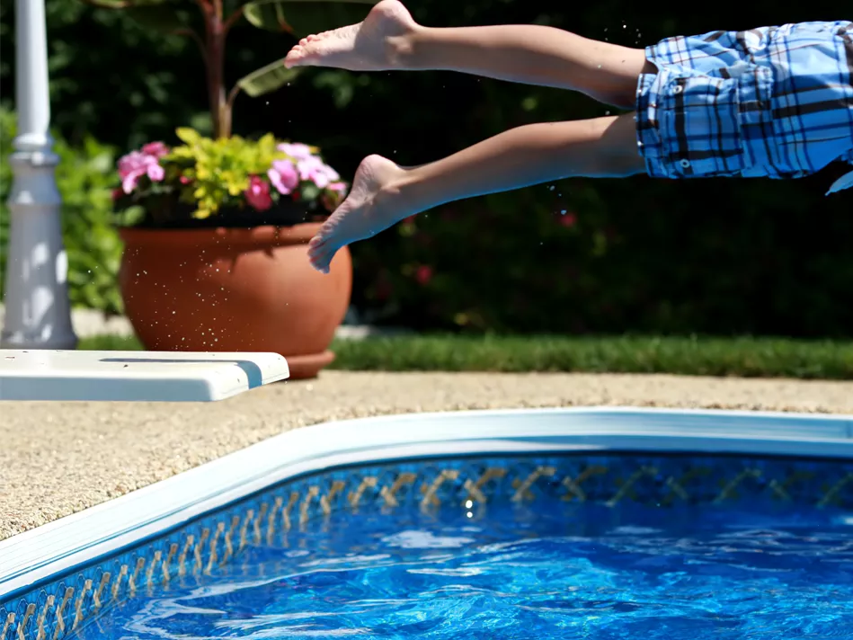 A young boy leaps off a diving board into a pool